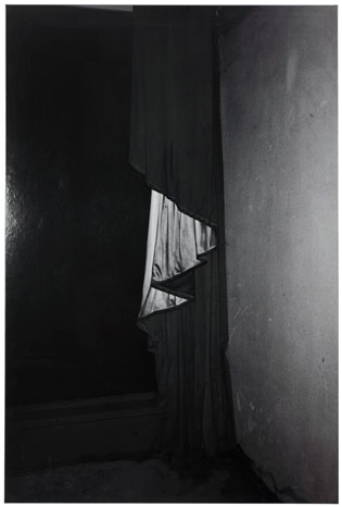 G.C.-G.E.-97, 1997: A black-and-white photograph by Dirk Braeckman. The image is blurred and obscured, with indistinct subjects that could be part of a draped theatrical curtain next to a wall. The atmosphere is mysterious and enigmatic, inviting viewers to interpret the scene.