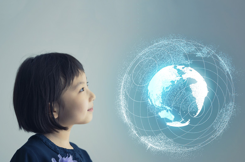 Photo d'archives d'une jeune fille asiatique sur un fond gris-bleu regardant un globe virtuel.